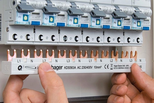 Elektriker montiert Hager KDS563A Phasenschiene waagerecht an Gruppe Einbaugeräten