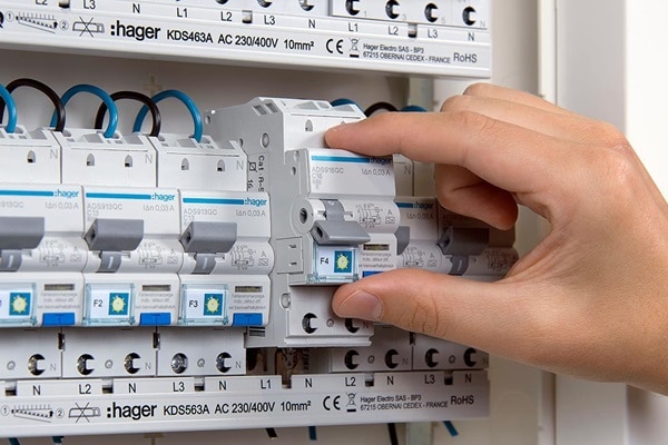 Elektriker montiert Hager ADS916QC Fehlerstrom-Leitungsschutzschalter (FI-LS-Schalter) an Phasenschiene in Hager Zählerschrank