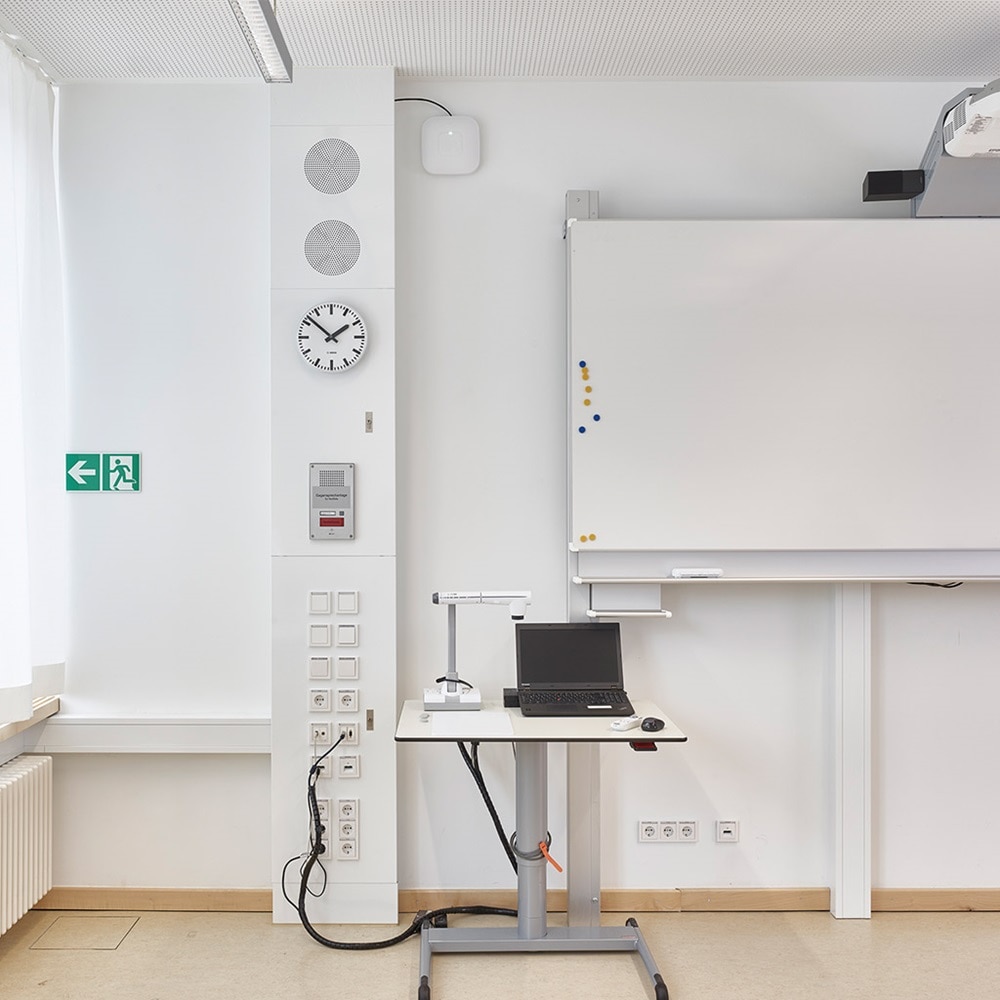 Blick in Klassenraum mit üppig ausgestattetet Hager Mediensäule, Notebooktisch und Whiteboard mit Projektor