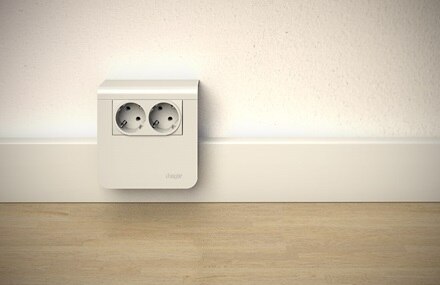 Blick auf Hager tehalit Sockelleistensystem in Verkehrsweiß, Sockelleiste mit Geräteträger und Einbaugerät 2-fach Steckdose