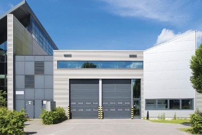 Modern industrial building with large windows and garage doors under a clear sky