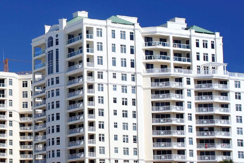 Modern white multi-story residential building against a clear blue sky