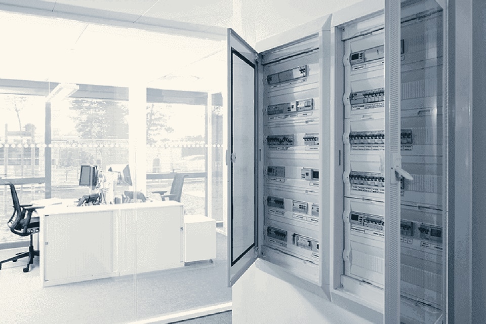Modern office interior with open electrical distribution panels containing circuit breakers