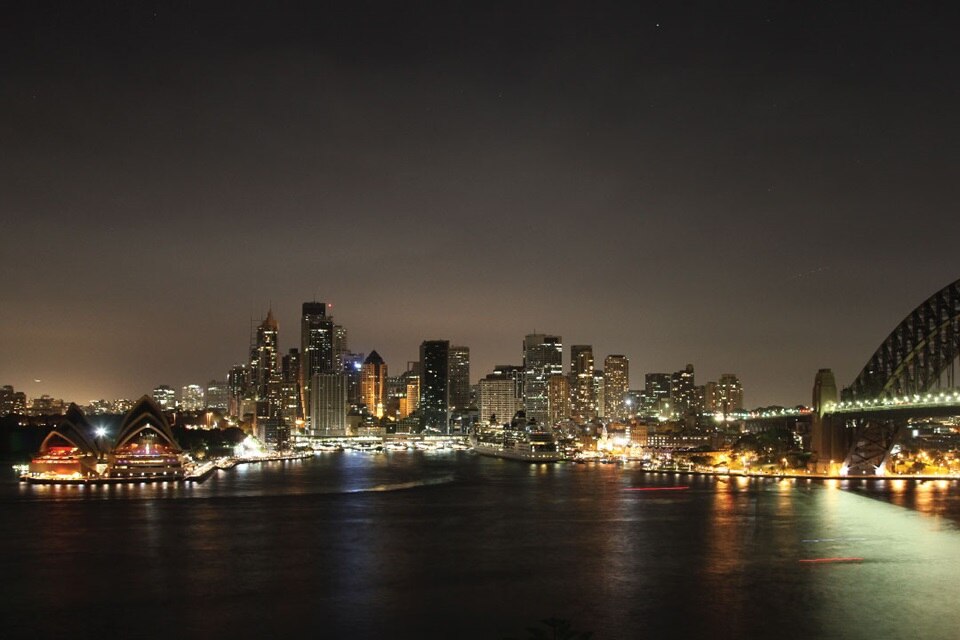 Night view of a cityscape with illuminated buildings and bridge over water