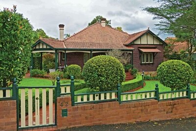 Traditional brick house with green garden and fencing