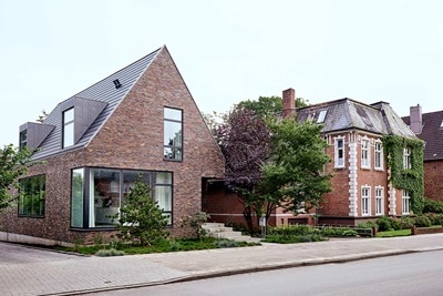 Moderne und traditionelle Wohnhäuser mit großen Fenstern und Ziegelsteinfassaden