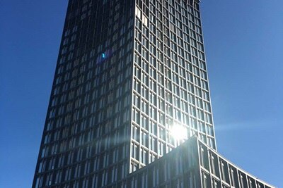Modernes Hochhaus-Bürogebäude vor klarem blauem Himmel mit Sonnenlichtreflexion