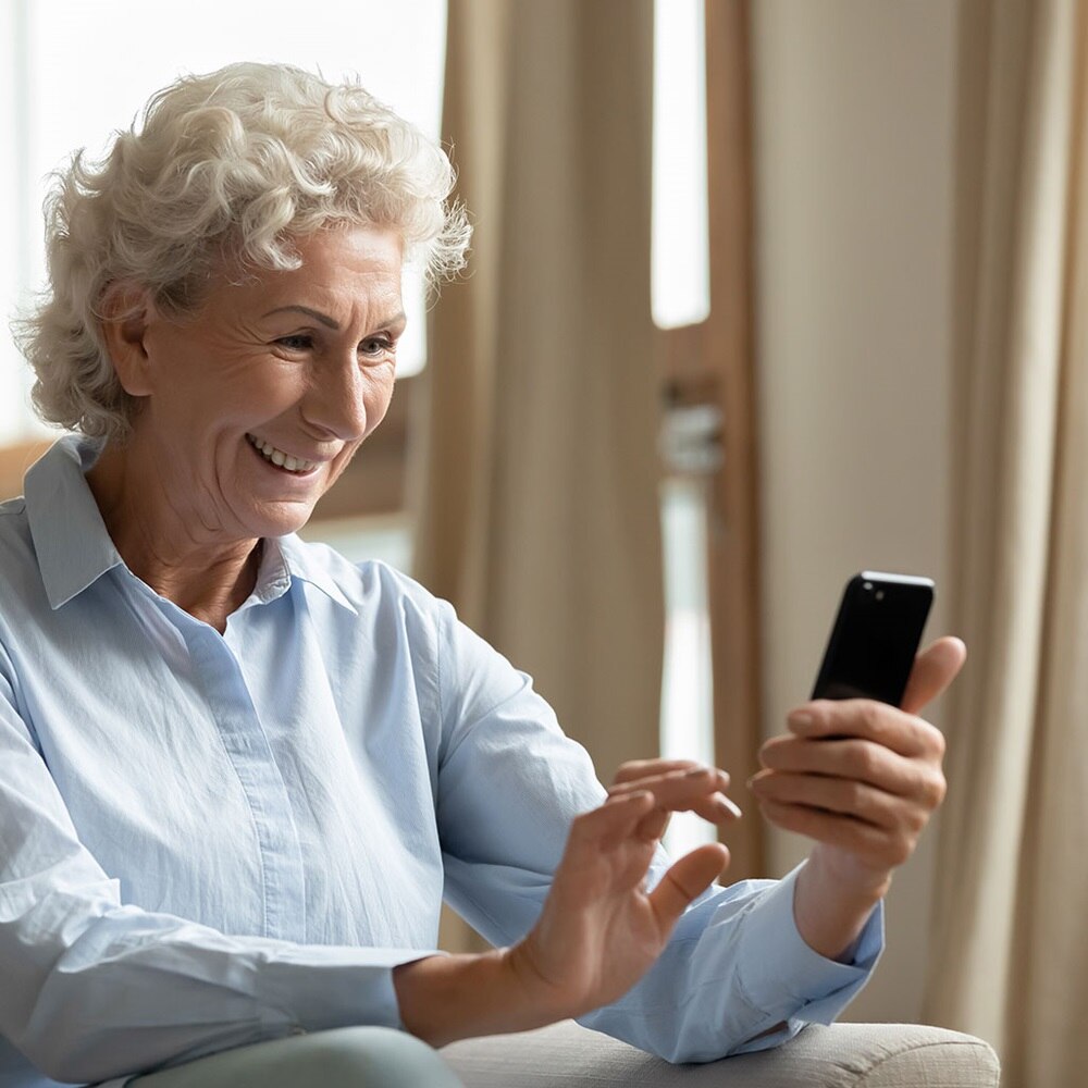 Eine Frau sitzt mit ihrem Handy auf der Couch