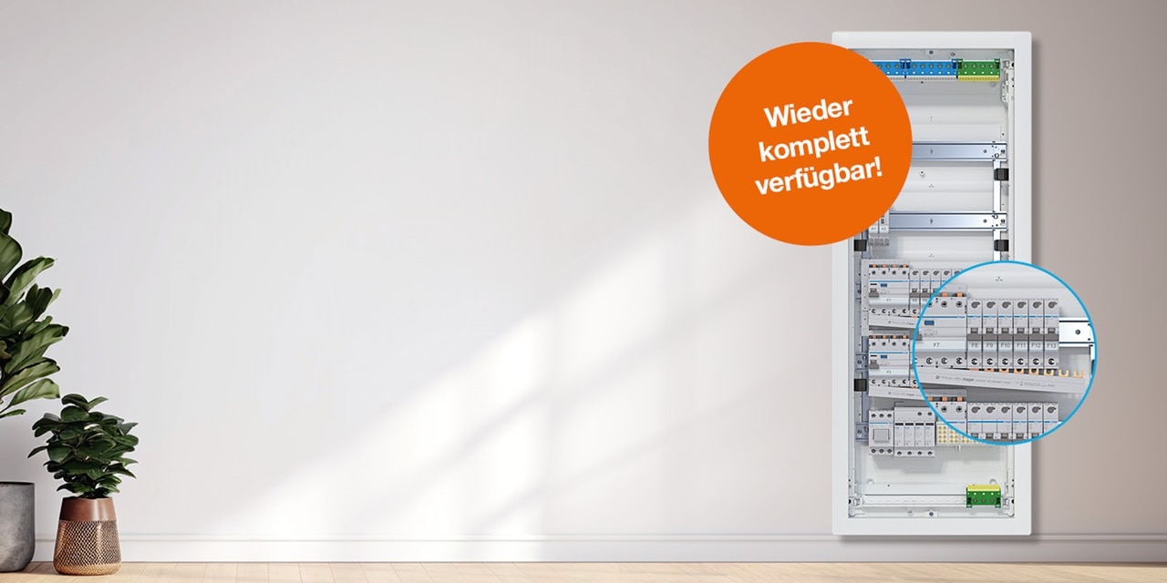 Elektroverteilungstafel mit Leitungsschutzschaltern und Modulen in einem Wohnbereich, mit dem deutschen Slogan 'Wieder komplett verfügbar!'