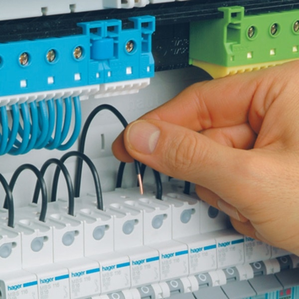 Die Hand eines Elektrohandwerkers steckt eine Leitung in ein Reiheneinbaugerät mit quickconnect