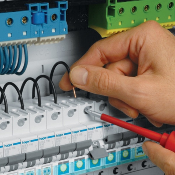 Die Hand eines Elektrohandwerkers steckt ein Prüfgerät in eine fingersichere IP2x-Prüföffnung eines Reiheneinbaugeräts mit quickconnect-System