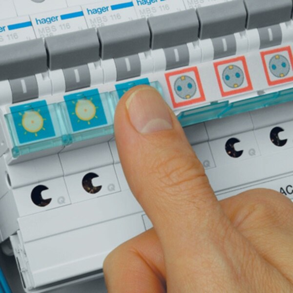 Eine Hand schließt die Schutzkappe über den Beschriftungsstreifen einer Reihe mit Leistungsschutzschaltern