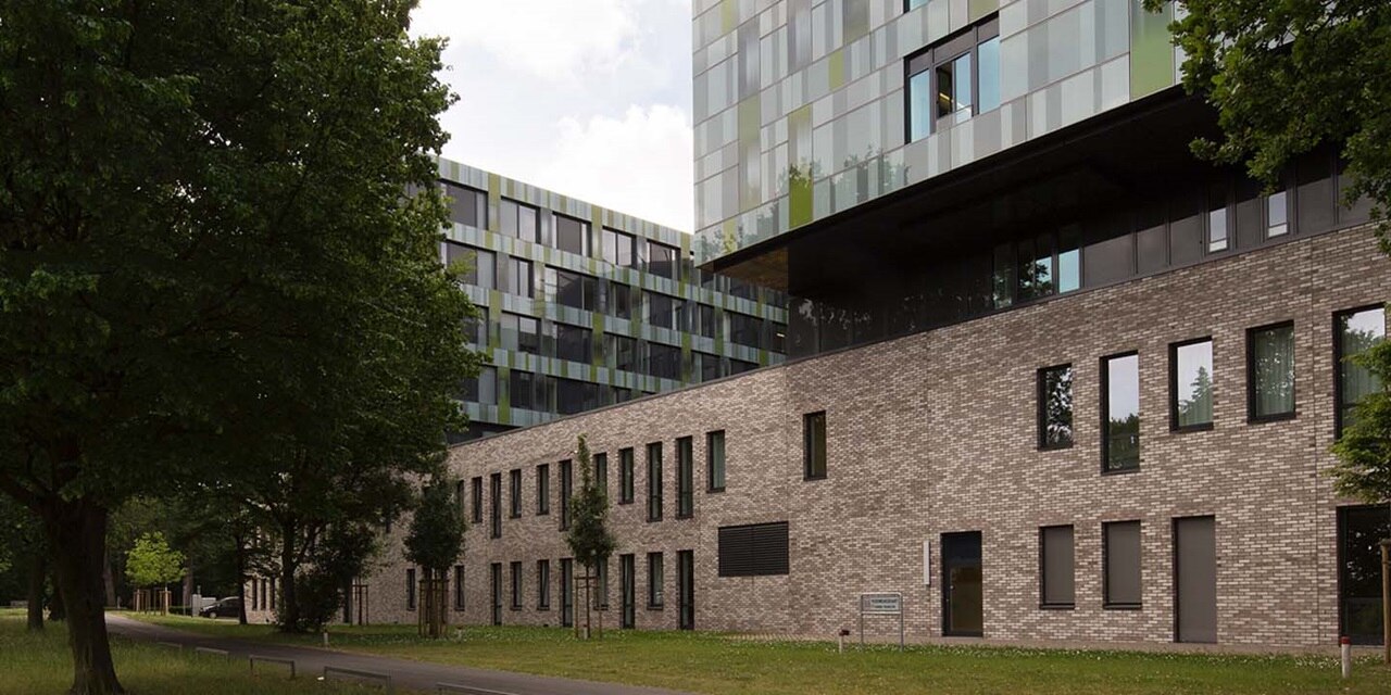 Moderne Bürogebäude mit großen Fenstern umgeben von grünen Bäumen