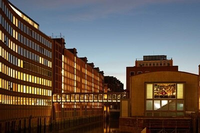 Moderne Bürogebäude bei Dämmerung beleuchtet mit Spiegelungen auf der Wasseroberfläche