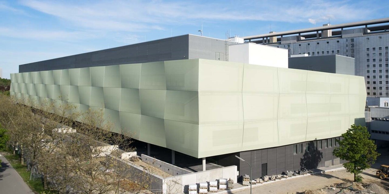 Moderne grüne Gebäudefassade mit geometrischem Design vor klarem Himmel