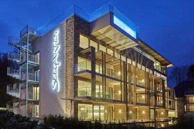 Modernes Gebäude in der Abenddämmerung mit beleuchteter Beschilderung und architektonischer Beleuchtung