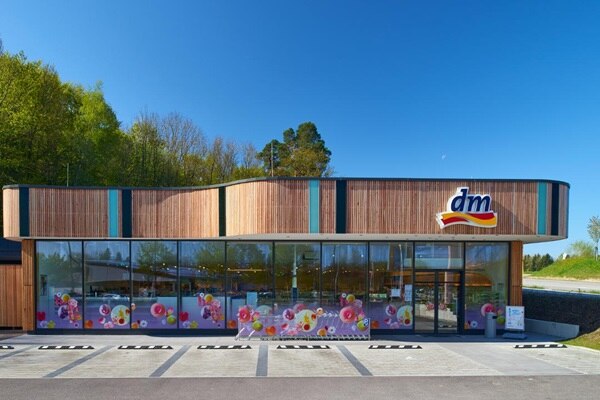 Moderne Holzfassade eines Gewerbegebäudes mit großen Glasfenstern und klarem blauen Himmel