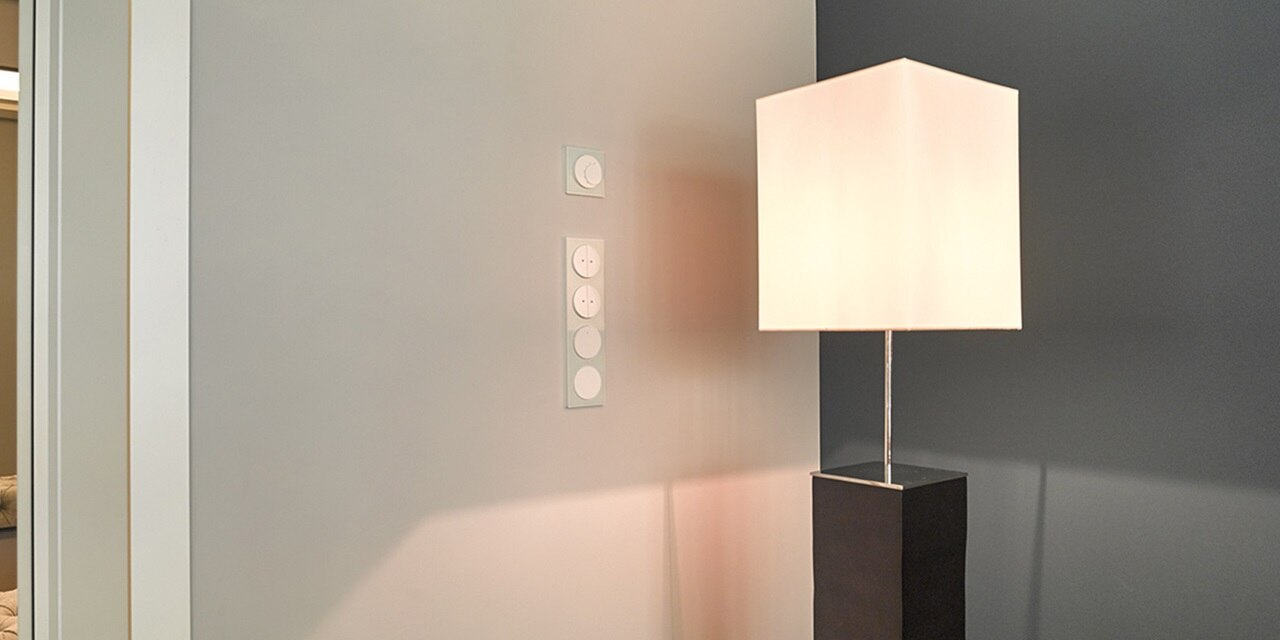 Modernes Zimmer mit Lichtschalter und Steckdosen an der Wand neben der Tischlampe