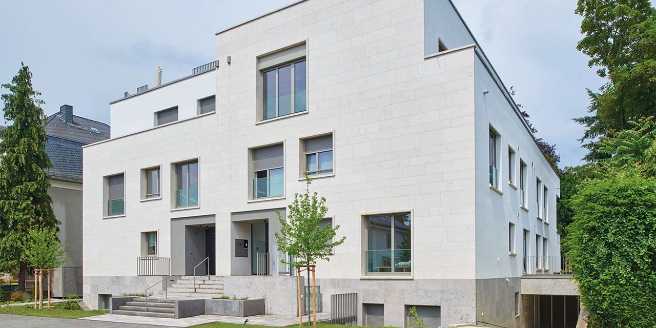 Modernes Mehrfamilienhaus mit einer Fassade aus großen Fenstern und Balkonen