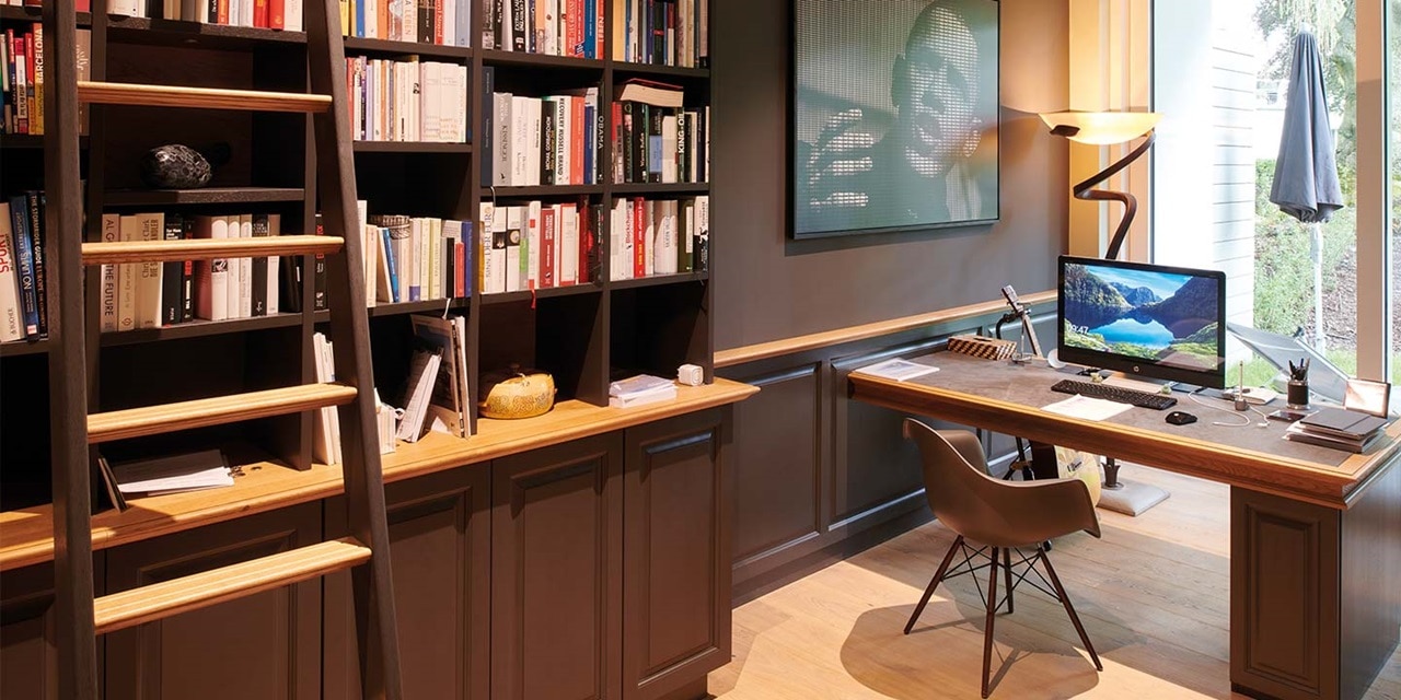 Häusliches Büro mit Holzschreibtisch, Bücherregalen, modernem Computer und Designerlampe