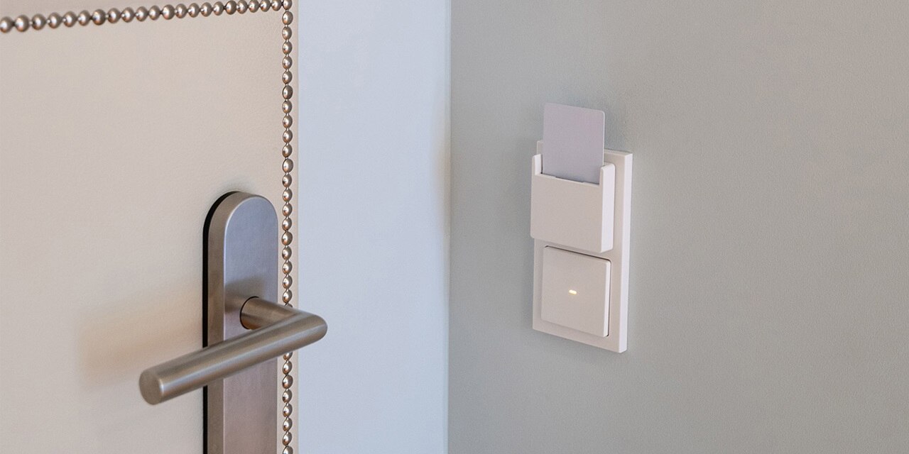 Moderner Lichtschalter an der Wand neben Türgriff und Spiegel
