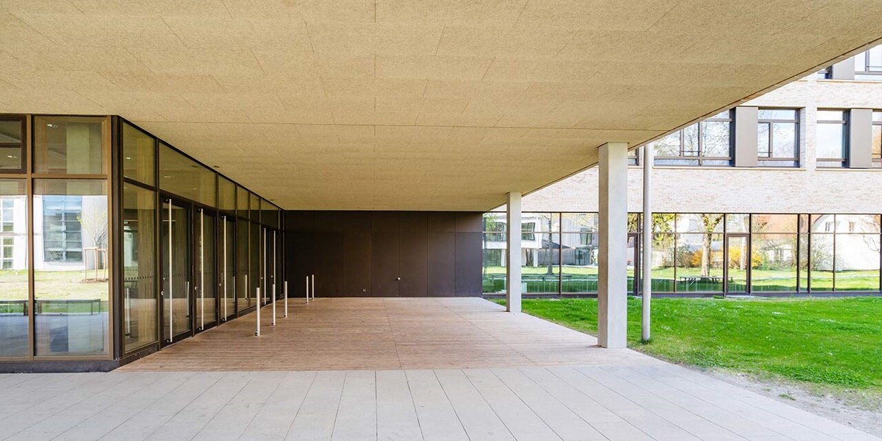 Moderne Gebäudeaußenansicht mit großen Glasfenstern, auskragendem Dach und Betonsäulen