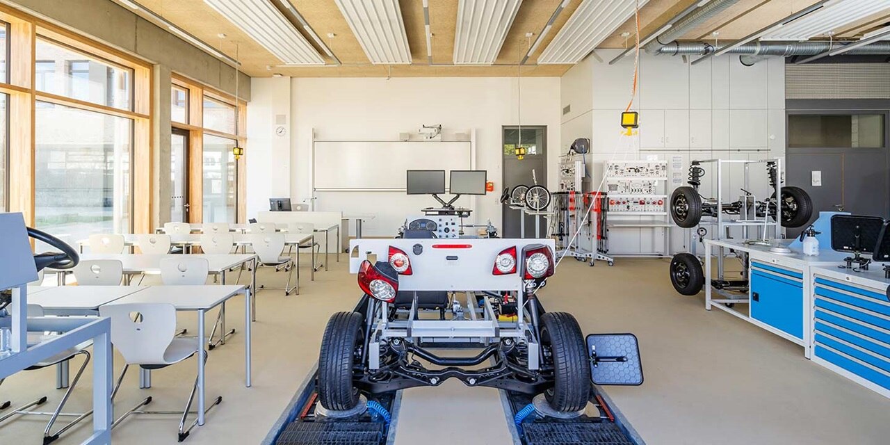 Moderne Kfz-Schulungsklasse mit elektrischem Auto-Modell, Arbeitsstationen und Lehrmitteln