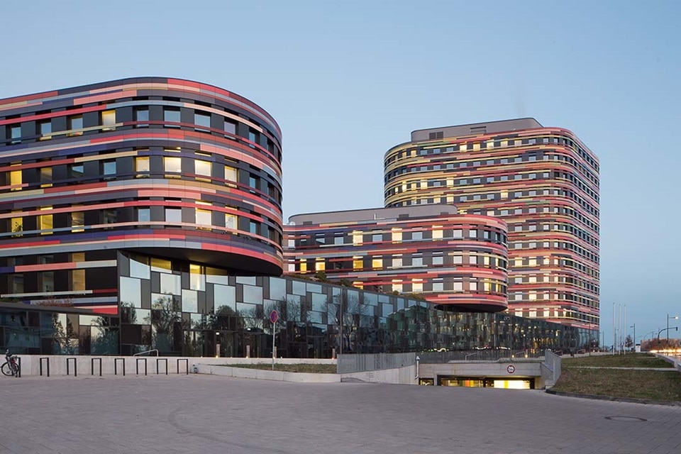 Moderne Geschäftsgebäude mit geschwungener Architektur und reflektierenden Glasfassaden in der Abenddämmerung
