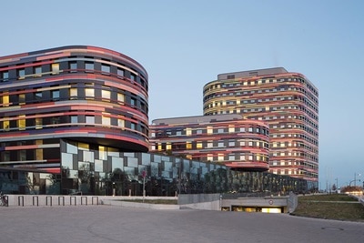 Moderne Bürogebäude mit geschwungener Architektur und reflektierender Glasfassade in der Abenddämmerung
