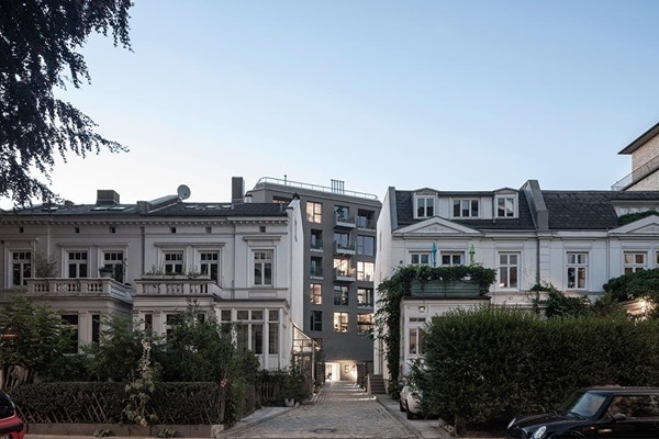 Traditionelle Wohngebäude mit Balkonen neben einem modernen Apartmentkomplex mit einer elektrischen Satellitenschüssel auf dem Dach sichtbar