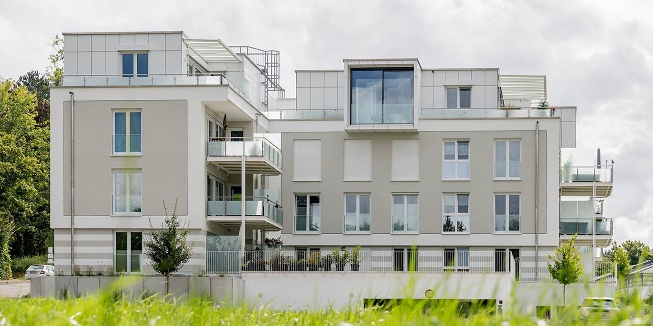 Modernes Mehrfamilienhaus mit Balkonen und großen Fenstern