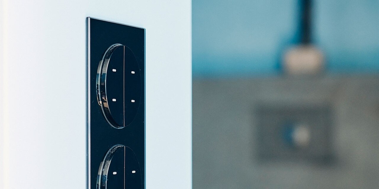 Doppelte Steckdose mit modernem schwarzem Design an einer blauen Wand, mit unscharfem Hintergrund