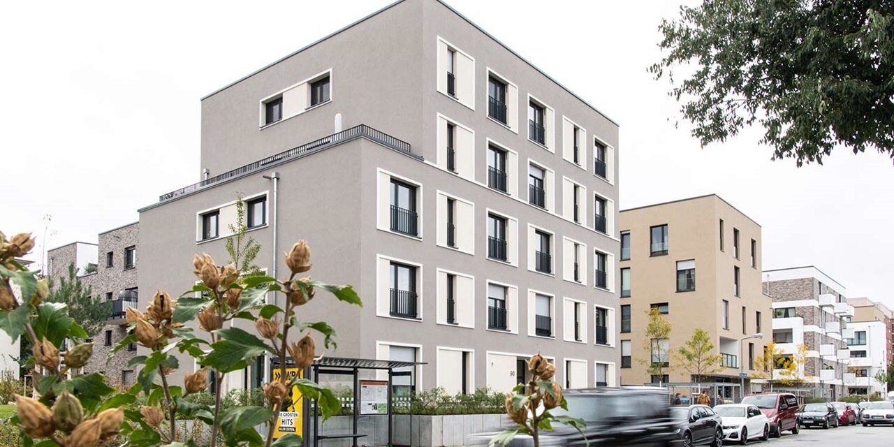 Moderne Wohngebäude mit Balkonen und einem unscharfen Auto im Vordergrund