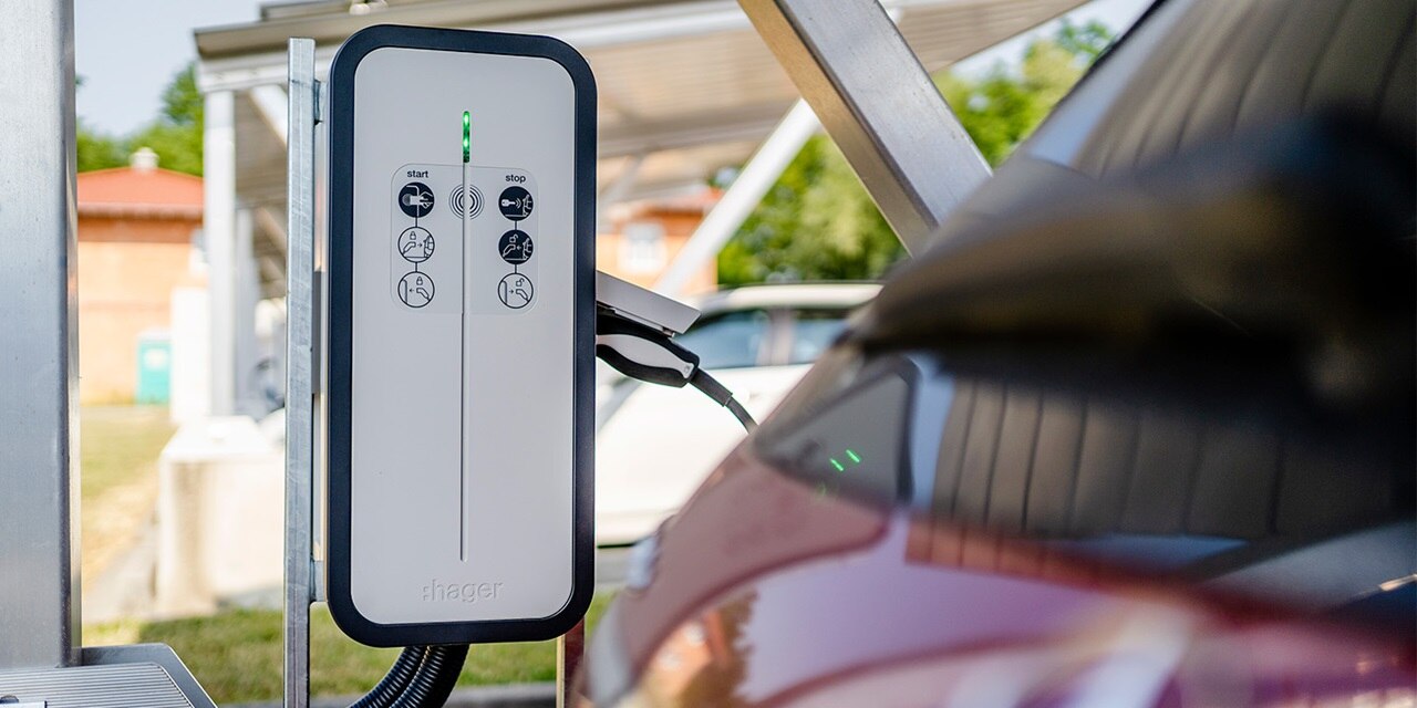 Hager-Ladestation für Elektrofahrzeuge mit im Vordergrund ladendem Auto