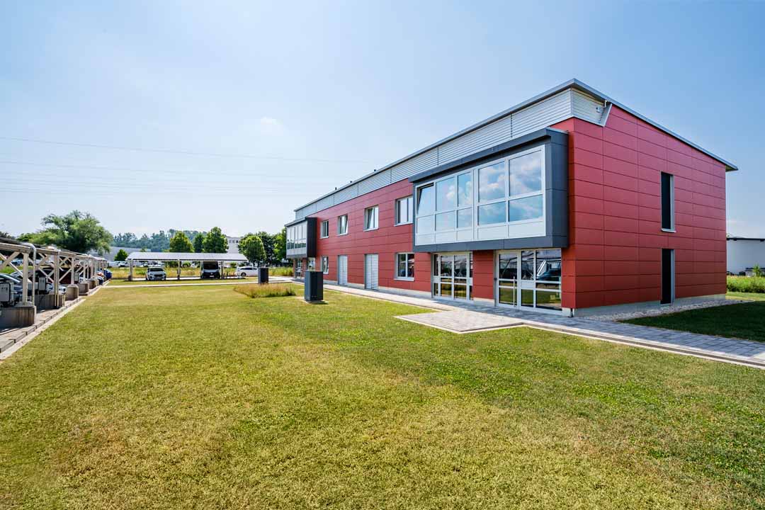 Modernes Gewerbegebäude mit großer Glasfassade und Gehweg an einem klaren Tag