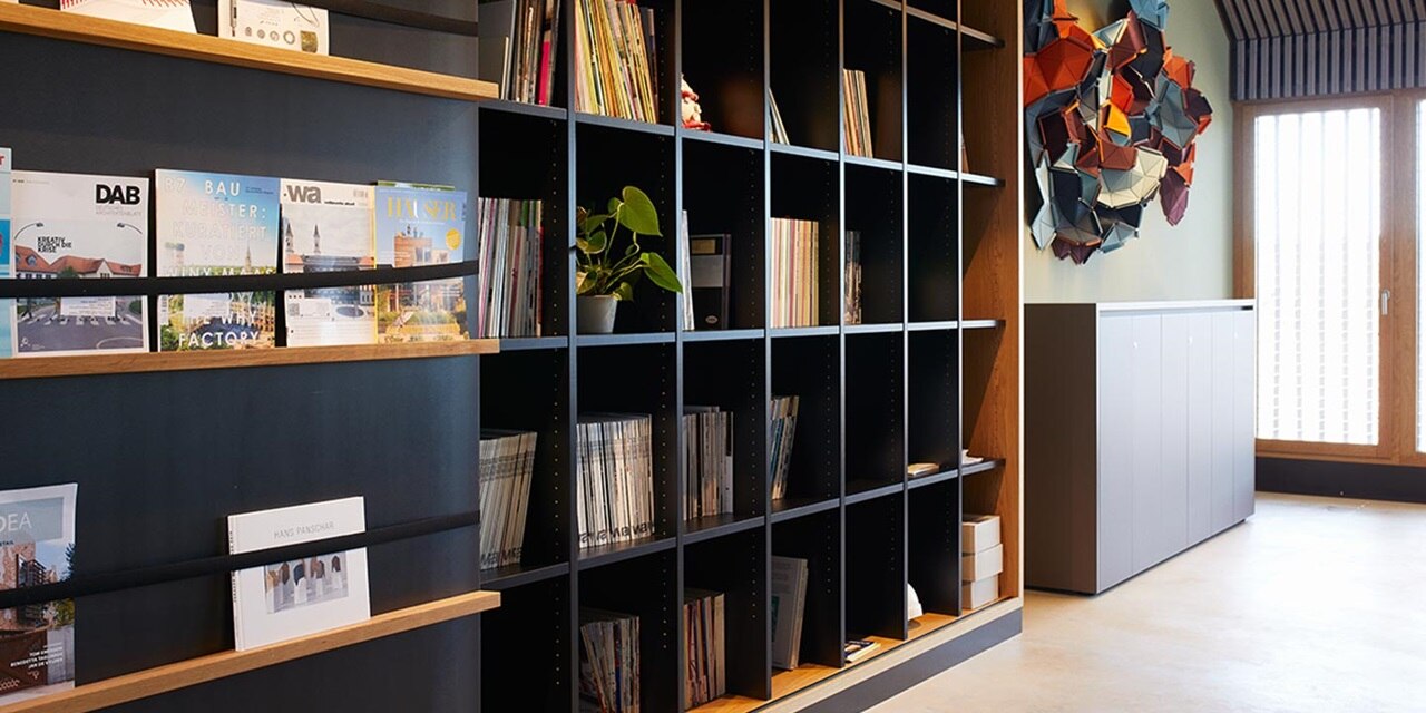 Modernes Bürointerieur mit Bücherregal, dekorativer Wandkunst und elektrischem Verteilerkasten