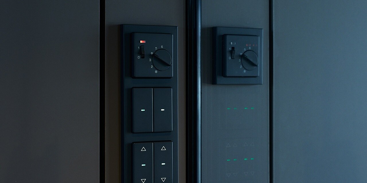 Moderne Smart-Home-Steuerungspanele mit Schaltern, Drehreglern und Statusanzeigen an einer dunklen Wand