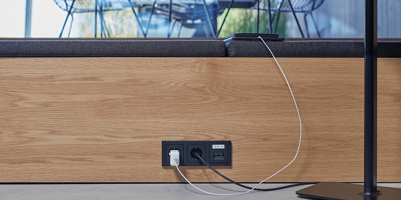Bürotisch mit integrierten Steckdosen und USB-Anschlüssen zum Laden, angeschlossene Kabel
