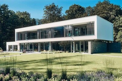 Modernes zweistöckiges Haus mit großen Fenstern und einem angelegten Garten