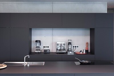 Küchenzeile mit Kaffeemaschine, -mühle und Mixer, angeschlossen an Steckdosen im Design der Serie Berker R.1
