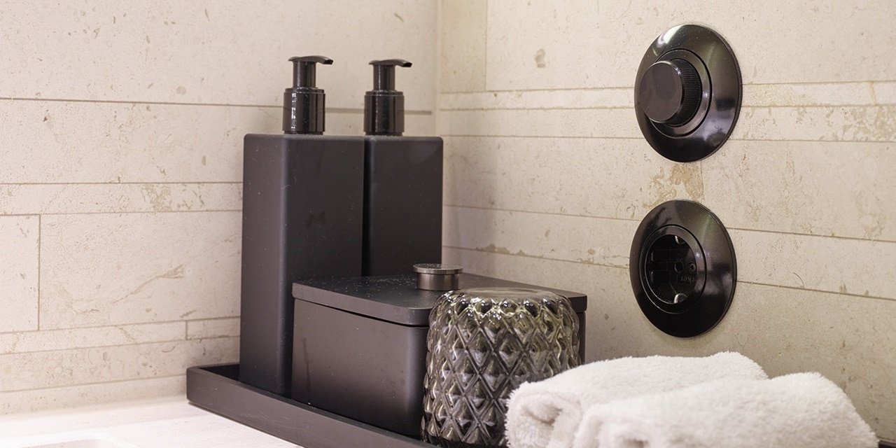 Modernes Badezimmer mit schwarzen dekorativen Seifenspendern und eingebauter Wandsteckdose und Thermostatregelung