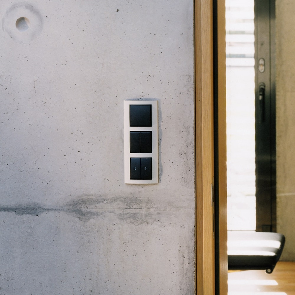 Beispiel einer Installation Berker B3 Lichtschalter 1-fach und 2-fach mit Wippe in Schwarz und Jalousieschalter in Schwarz und Rahmen in Silber an Sichtbetonwand Innenbereich