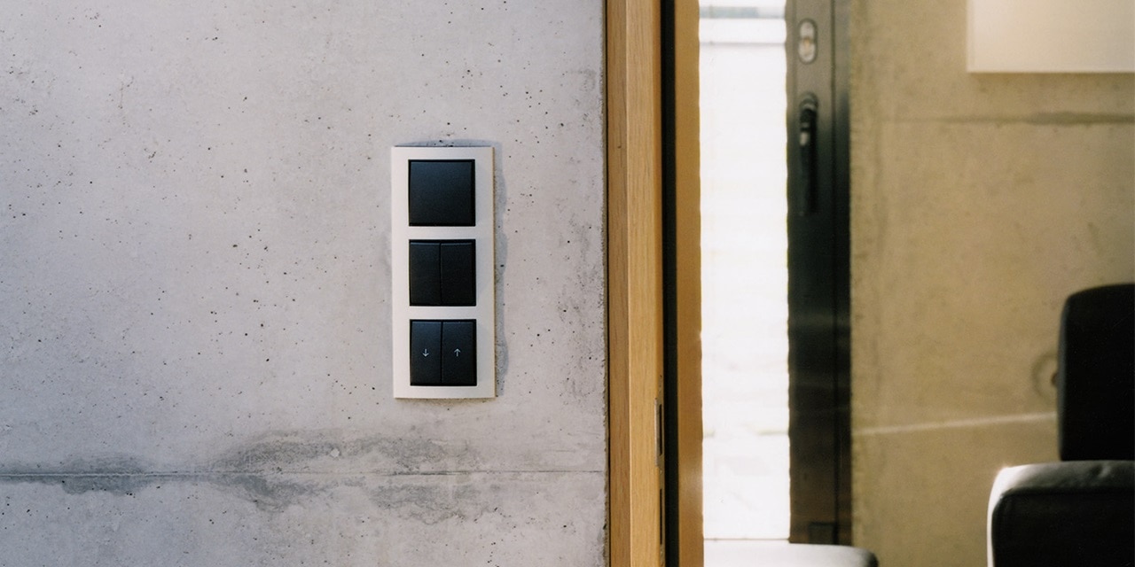 Moderne Lichtschalter an einer Betonwand neben einem Holztürrahmen