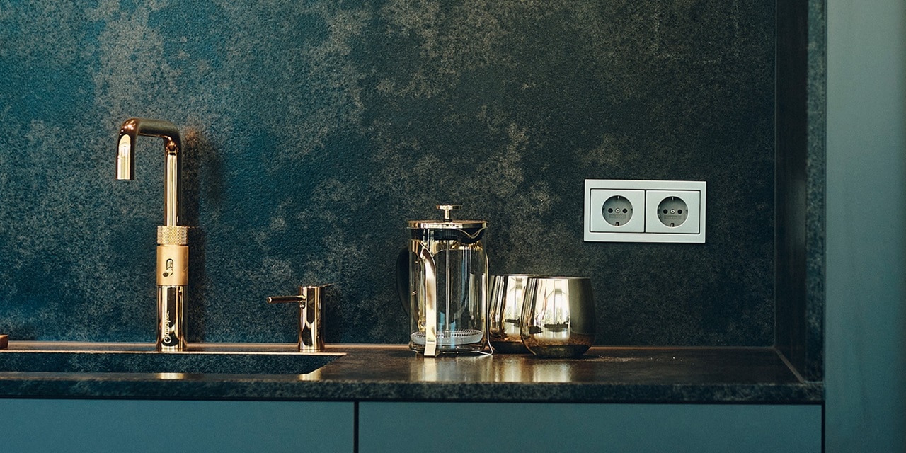 Moderne Küche mit einer metallischen Wasserhahn und einer Doppelsteckdose an einer dunkelblauen Wand