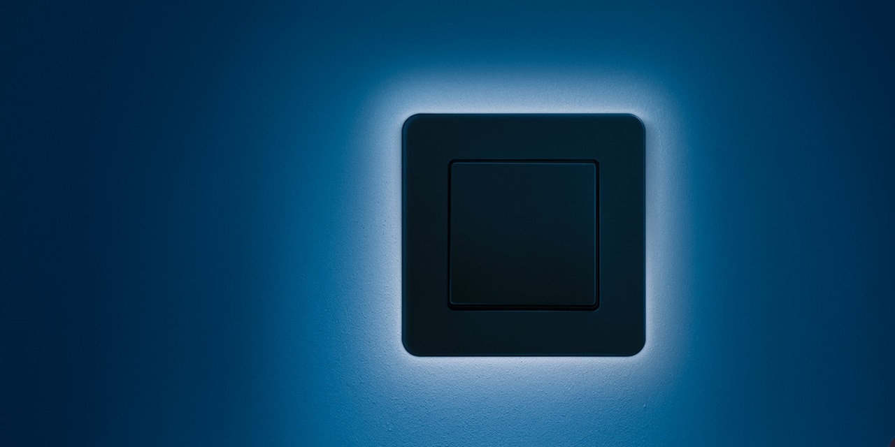 Moderner schwarzer Lichtschalter an einer blauen Wand mit weicher Beleuchtung