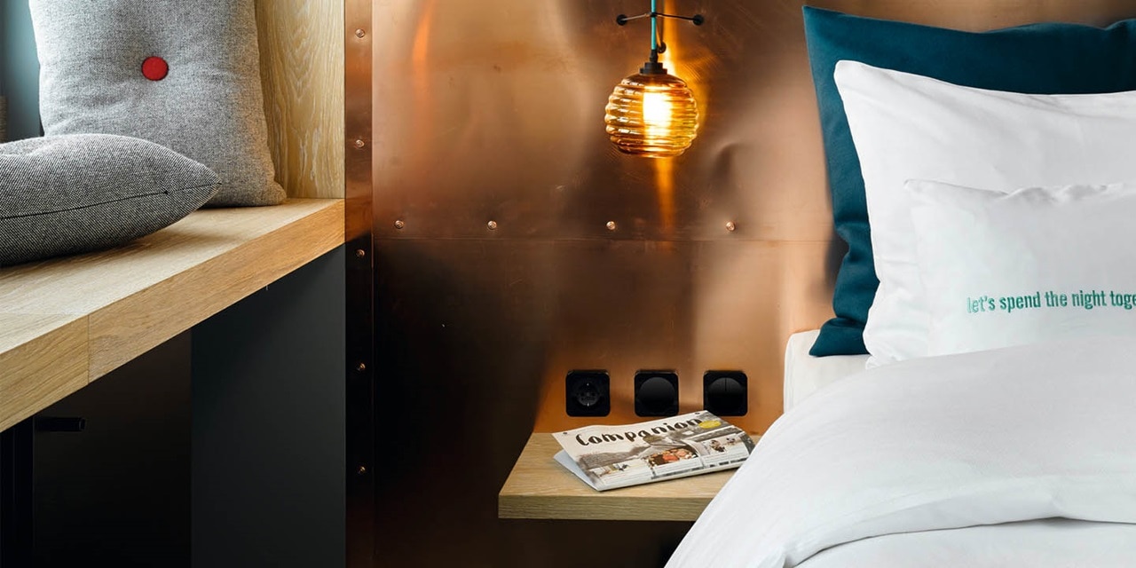 Modernes Schlafzimmerinterieur mit Designer-Hängeleuchte und wandmontierten elektrischen Schaltern und Steckdosen