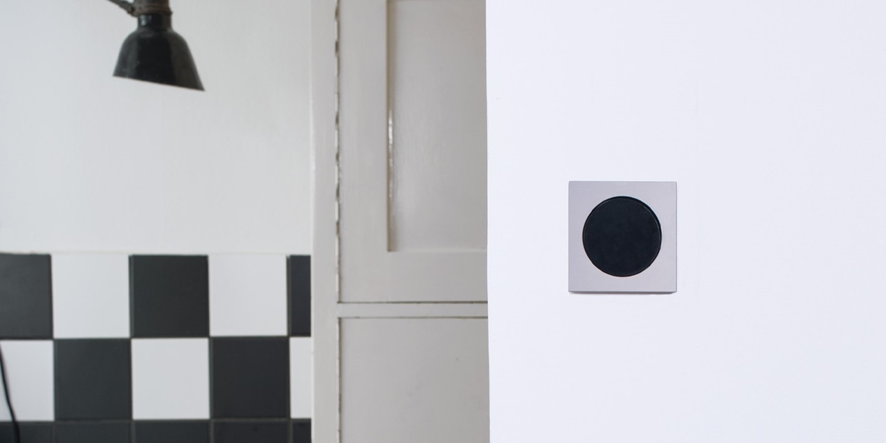 Moderner schwarzer Druckknopf-Lichtschalter an einer weißen Wand im minimalistischen Design