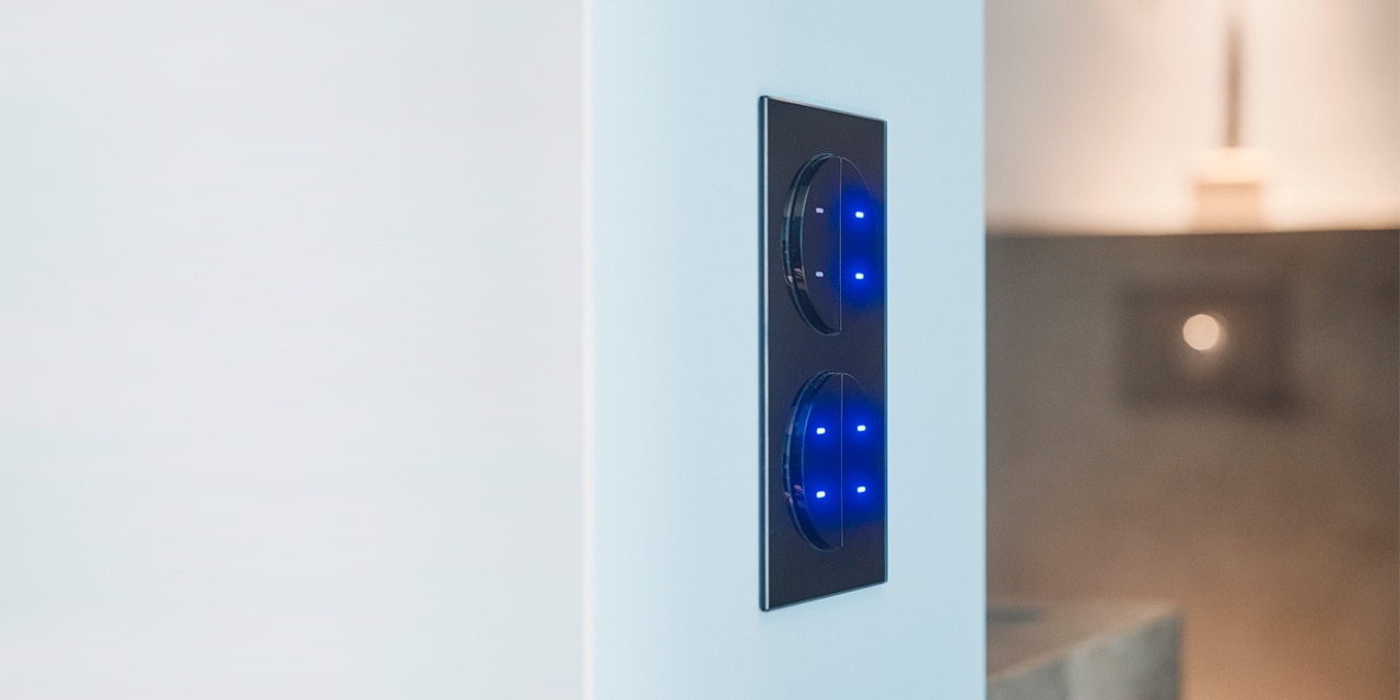 Moderne schwarze intelligente Lichtschalter mit blauen LED-Anzeigen an einer weißen Wand