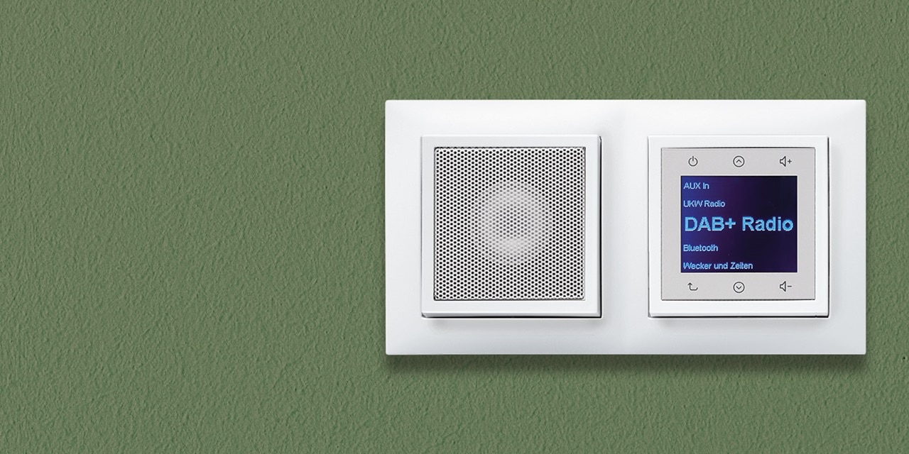 Wandmontierter weißer Lautsprecher und digitales Radio-Bedienfeld auf grünem Hintergrund für die intelligente Hausautomatisierung