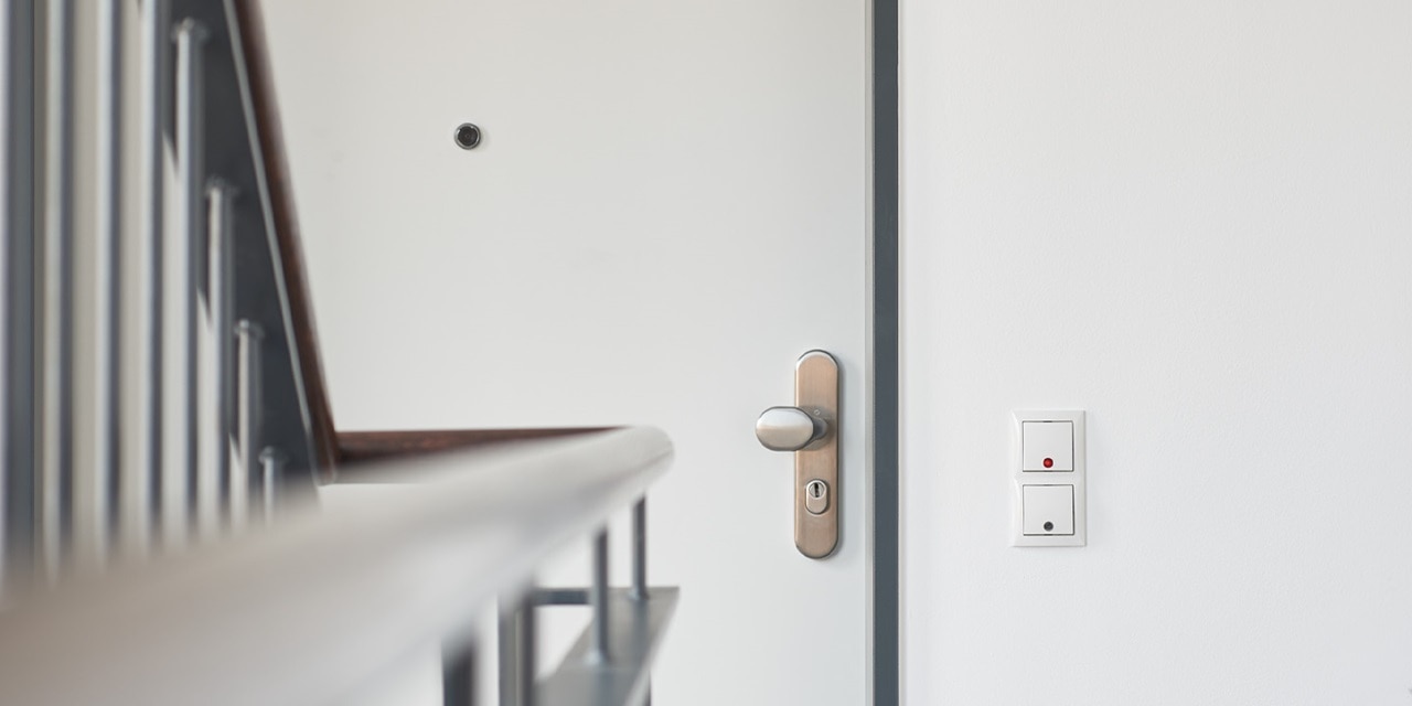 Moderner, weißer Elektroschalter und Steckdose an der Wand neben einer Holztür im Wohnbereich